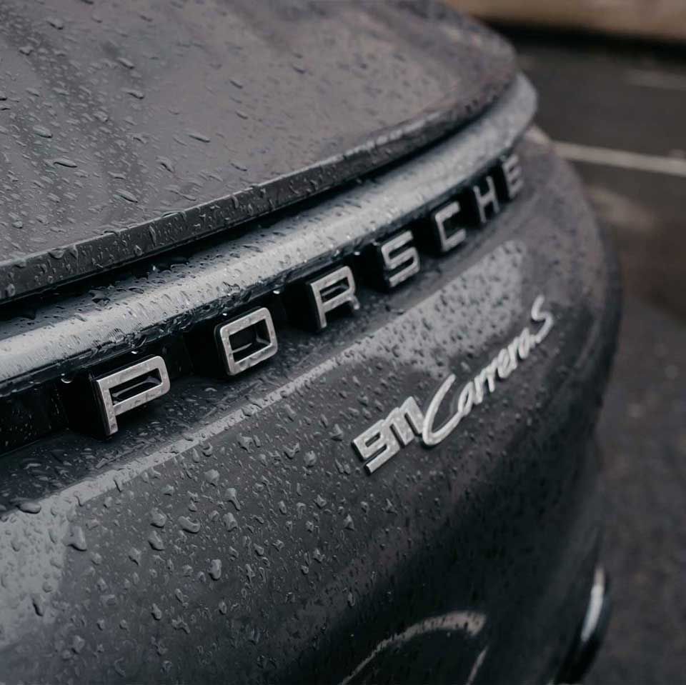 Rain on the rear lettering of a black Porsche 911 Carrera S