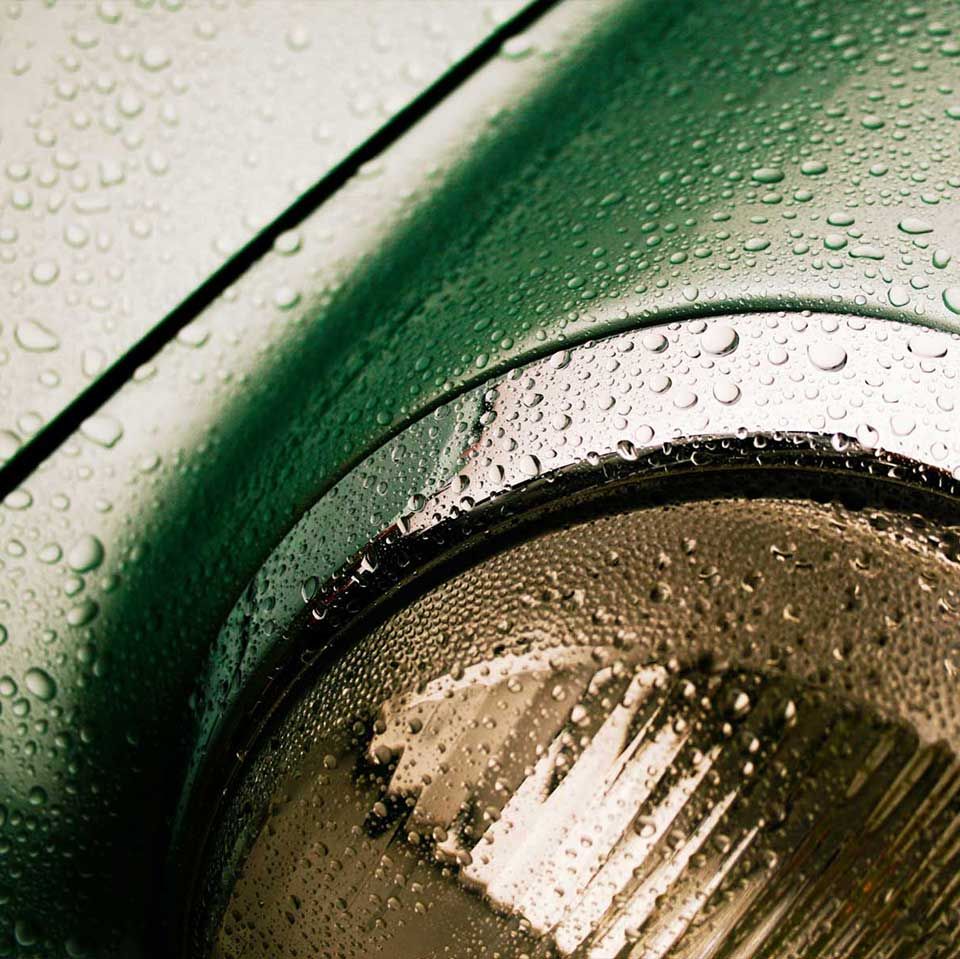 Raindrops on the headlight of a green classic Porsche 911