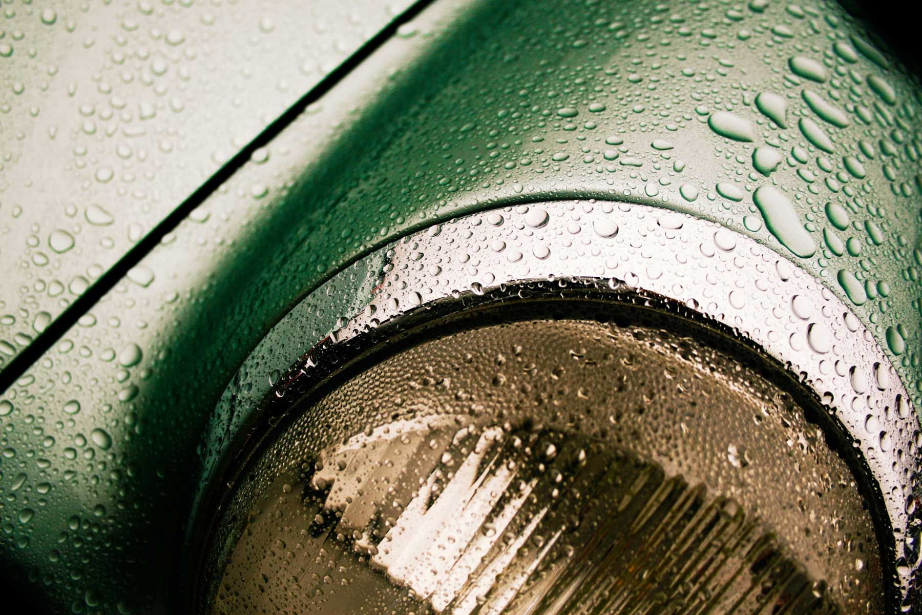 Green classic Porsche 911 headlight in the rain