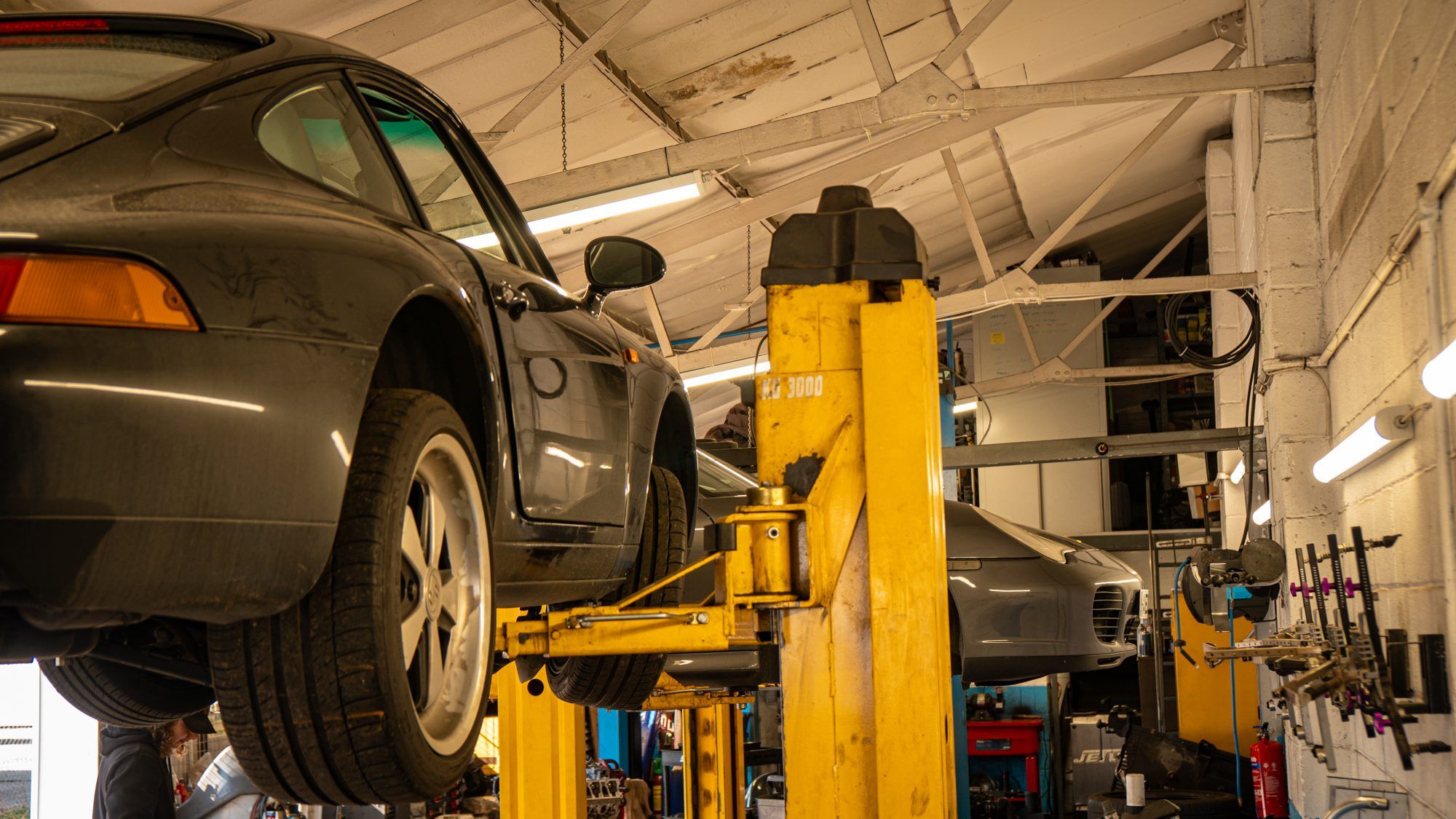Grey Porsche 911 raised on a workshop lift