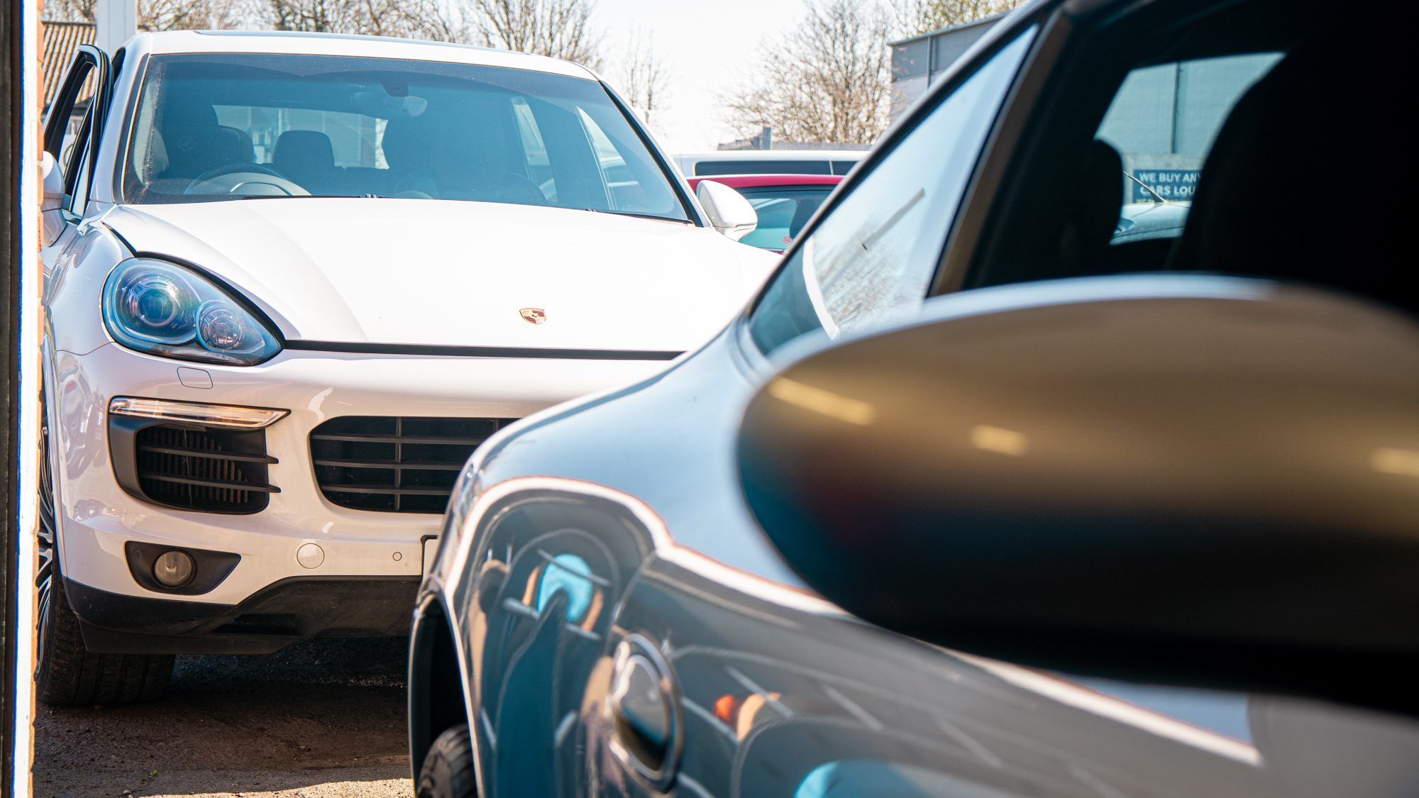 White Porsche Cayenne and a Porsche 911 outside the workshop
