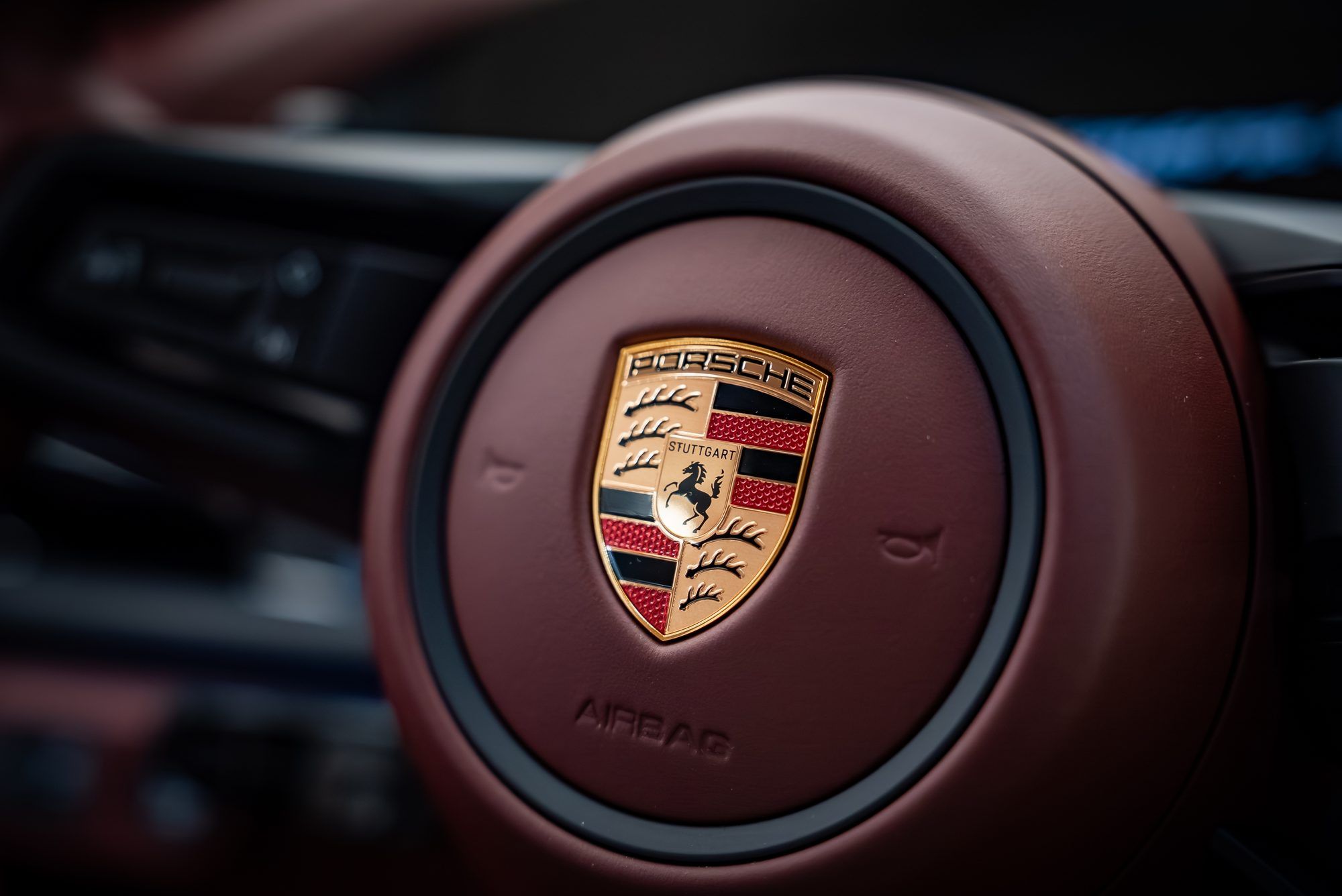 Porsche crest on the burgundy leather steering wheel of a Panamera