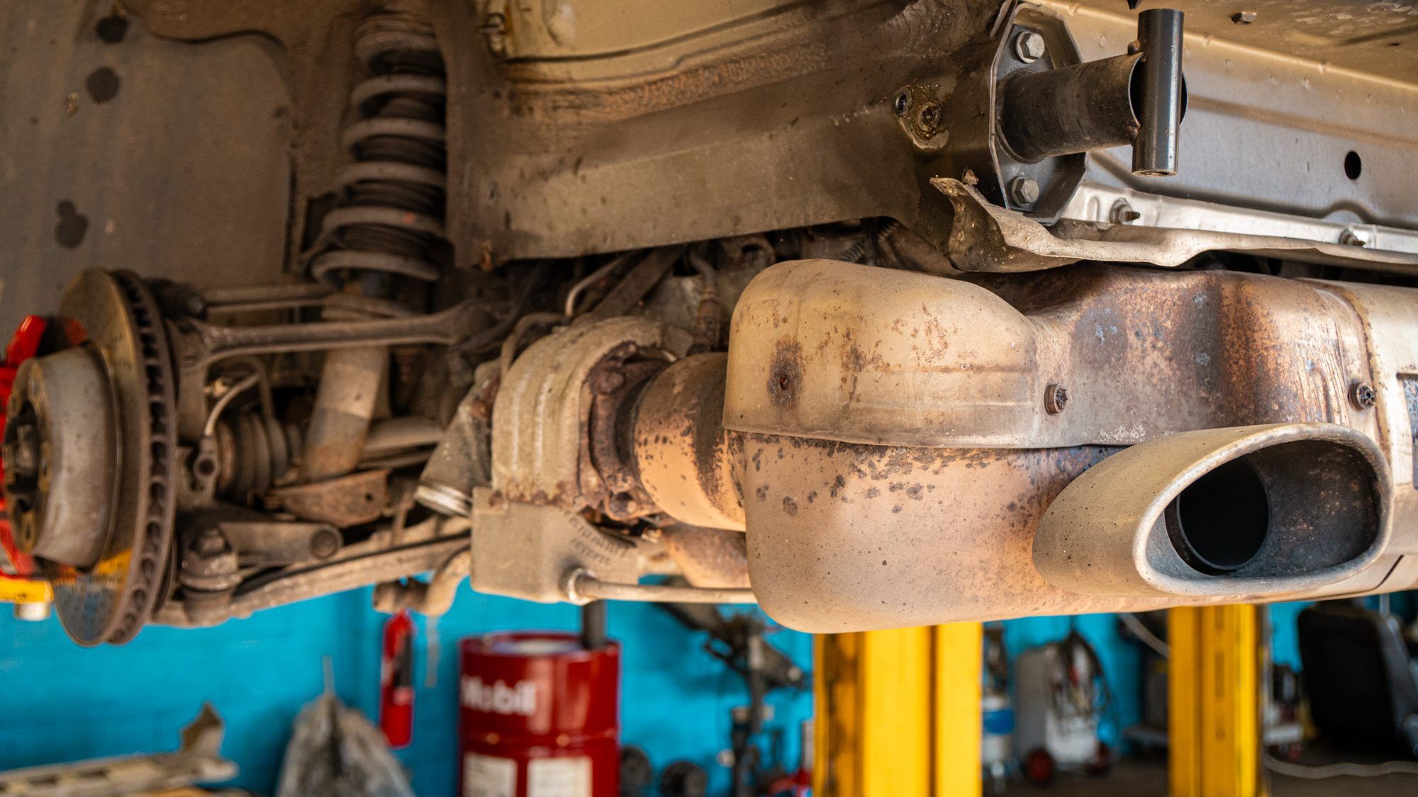 Underside of a Porsche on a lift, showing the exhaust and suspension
