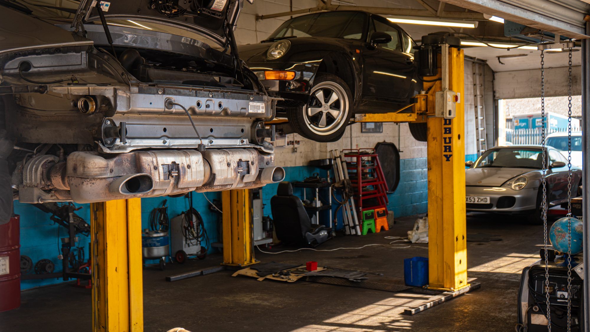 Inside the workshop, with Porsches raised on lifts