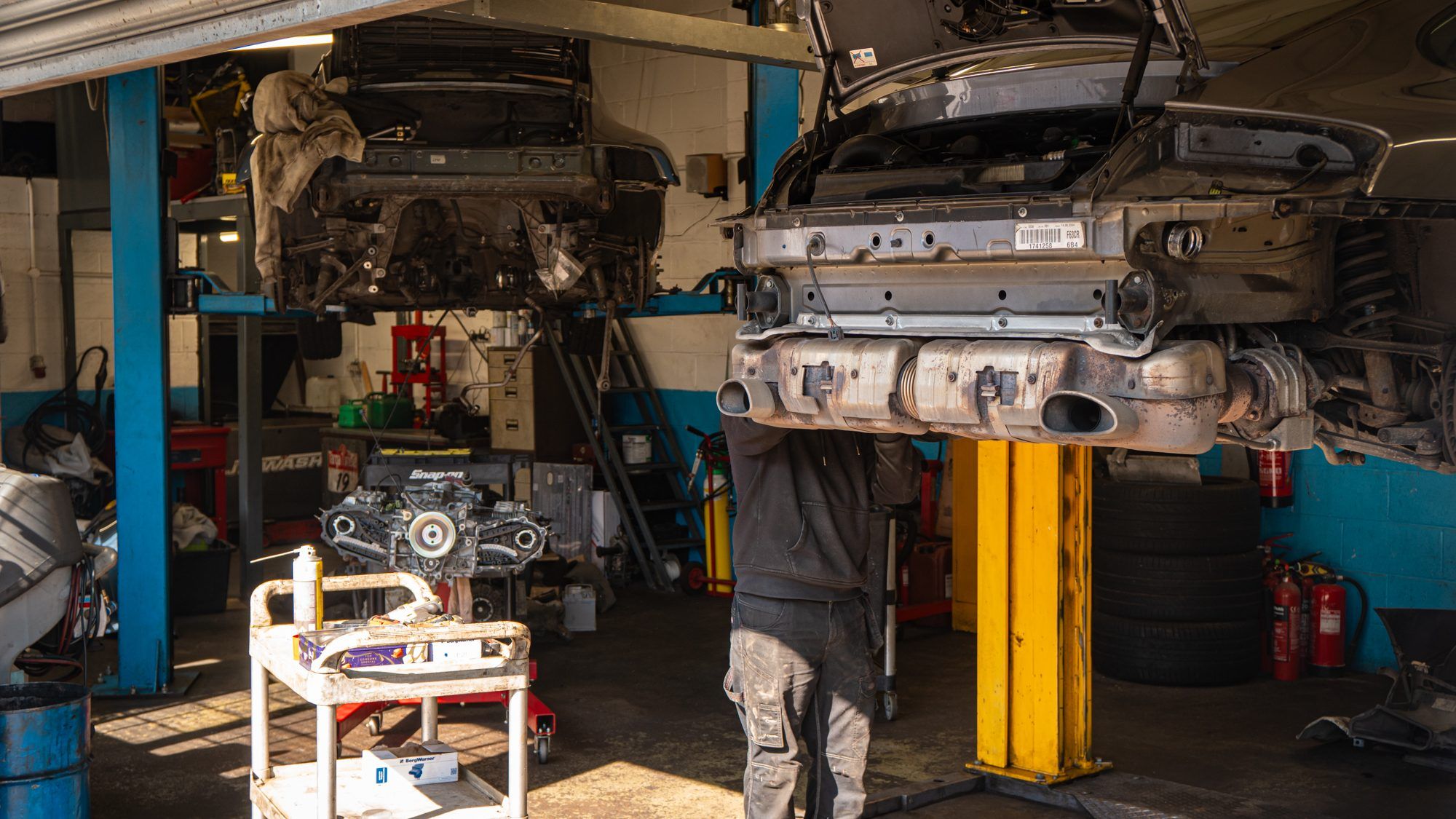 Technician at work under a Porsche in the workshop