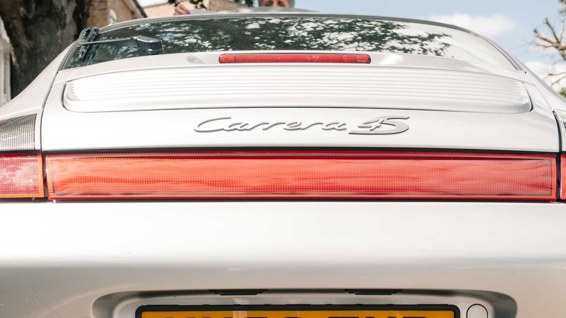Rear badge of a silver Porsche 911 Carrera 4S