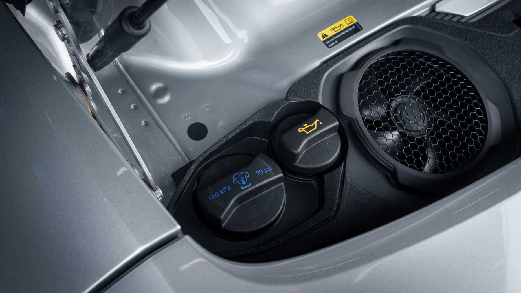 Coolant and oil filler caps under the front lid of a silver Porsche